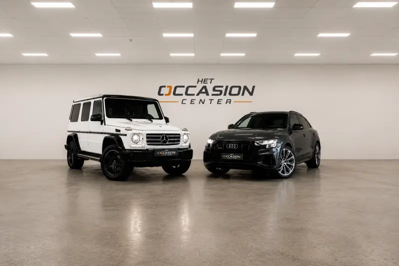 De showroom van Het Occasion Center met een Audi Q8 en een Mercedes G-klasse voor de logowand